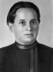 Porträt von Anna Schumann. Sie hat ein rundes Gesicht und kurze dunkle Haare. Sie schaut ernst in die Kamera. 