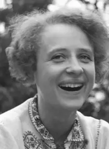 Helga von Hammerstein lacht fröhlich in die Kamera. Sie hat helles, gelocktes Haar, das ihr knapp über die Ohren reicht. 