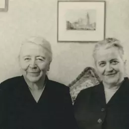 Die 61-jährige Marianne Hapig sitzt mit Marianne Pünder auf einem Sofa in einem Wohnzimmer. Sie lächeln in die Kamera.